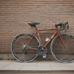 A bicycle leaning against a textured brick wall, showcasing a blend of vintage and modern aesthetics.