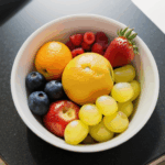 A bowl of vibrant fresh fruits, styled to perfection on a kitchen counter for visual appeal.
