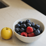 A bowl filled with various fresh fruits, offering a visual feast of colors on a kitchen counter.