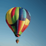 A colorful hot air balloon floating gracefully against a backdrop of fluffy white clouds.