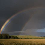 A stunning rainbow arches over the countryside, providing a serene and captivating view of nature's magnificence.