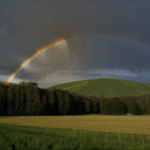 A majestic rainbow paints the sky over a peaceful countryside, offering a moment of serenity and visual splendor.