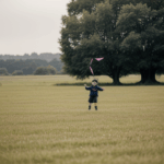 A scenic view of a child flying a kite in a wide open field, capturing the essence of family fun and childhood joy.