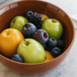 A beautifully styled bowl of fresh fruits on a kitchen counter, showcasing a healthy lifestyle.