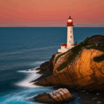 The silhouette of a lighthouse against a dramatic sunset sky on the rocky coast.