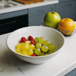 A kitchen counter with a decorative bowl of fresh fruits, emphasizing vibrant colors and health.