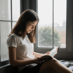 Peaceful book time, a woman reads contentedly by a sunlit window.