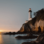 A romantic view of a lighthouse at sunset on a rocky shore.