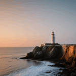 Serenity envelops a lighthouse as the sun sets over the rocky coast.