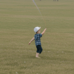 A close-up of a child's hands holding a kite string, capturing the essence of simple pleasures and joyful play.