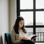 Sunlight and books create a perfect reading atmosphere for a woman by the window.
