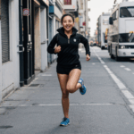 Vibrant girl in mid-run, experiencing the rush of city street fitness and exploration.